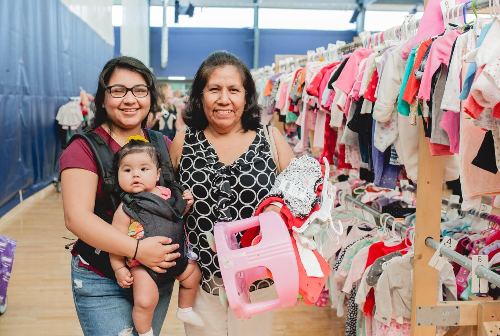 A mom, abuela and granddaughter attend a JBF sale in Dallas. Abuela is holding a babyseat.